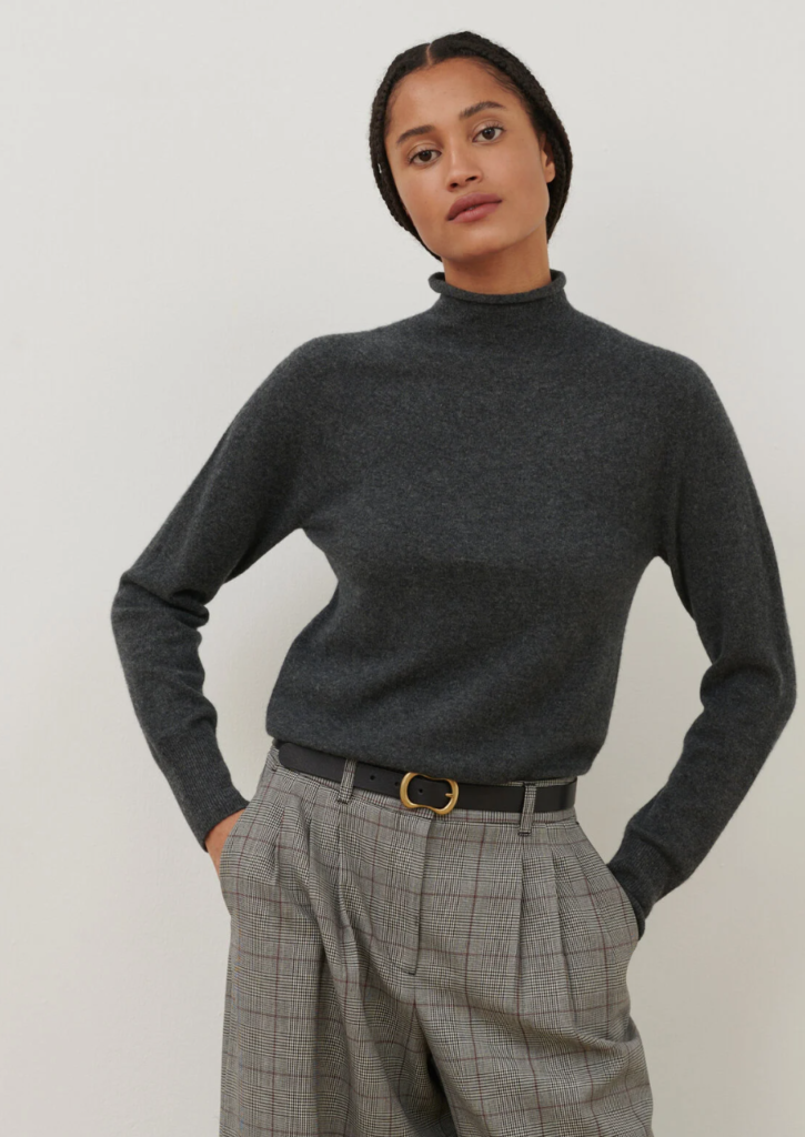 Pull en laine gris col roulé, porté avec un pantalon à carreaux dans un style professionnel décontracté.