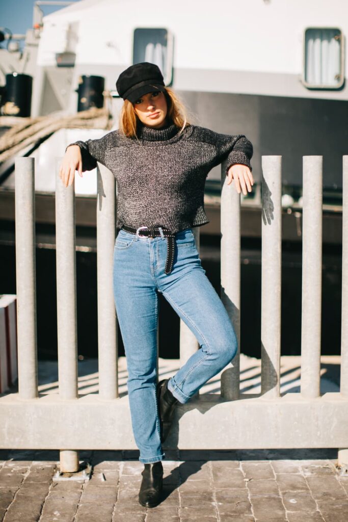 Femme en pull gris sur fond maritime.