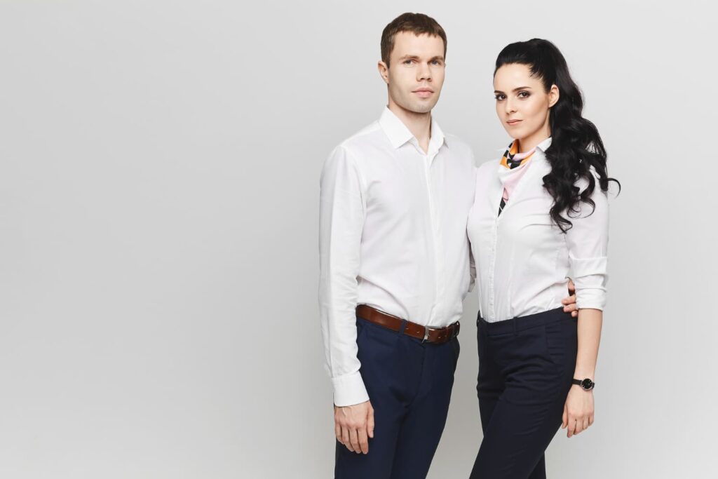 Deux personnes en chemises blanches posent ensemble.