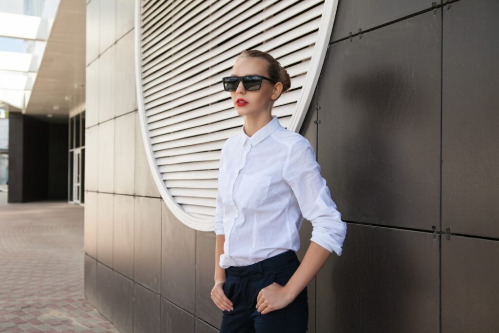Femme en chemise blanche et lunettes de soleil.