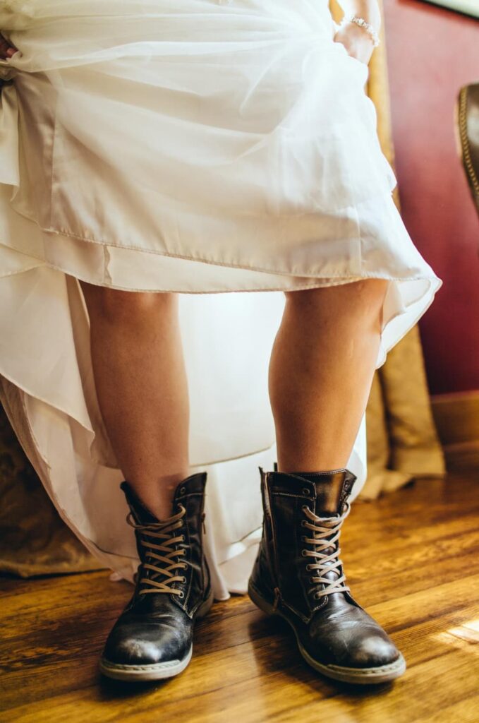 Robe blanche avec bottes noires sur plancher bois.