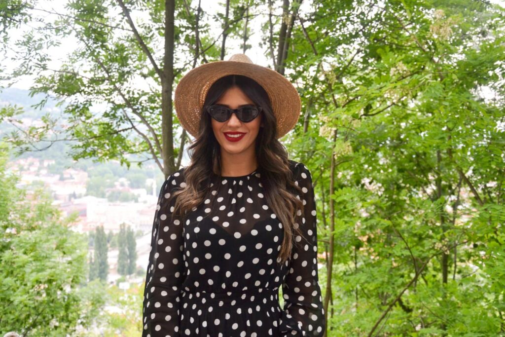 Femme souriante portant chapeau et lunettes de soleil.