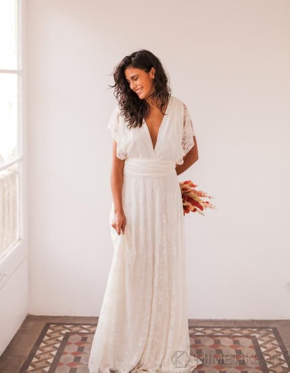 Femme souriante en robe de mariée blanche minimaliste.