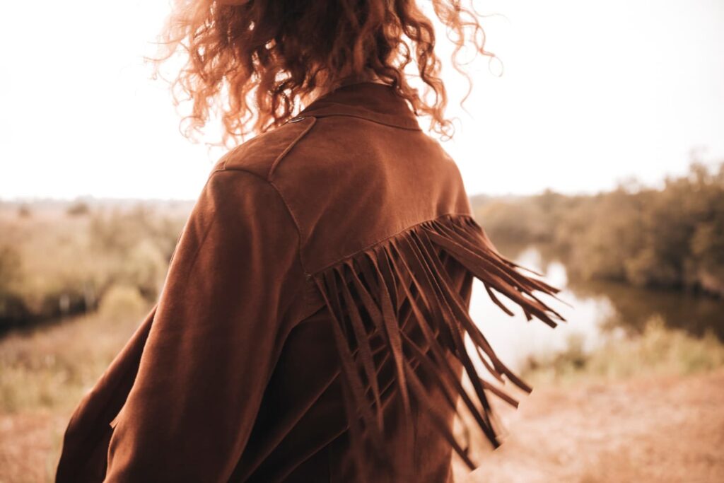 Personne avec veste à franges, paysage flou derrière