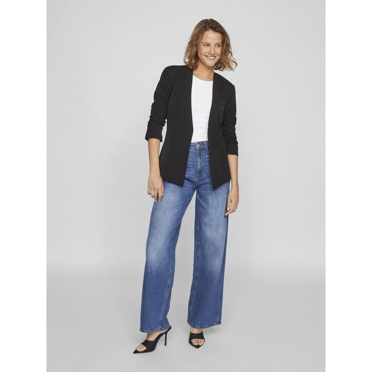 Person smiling wearing black jacket and wide-leg jeans.