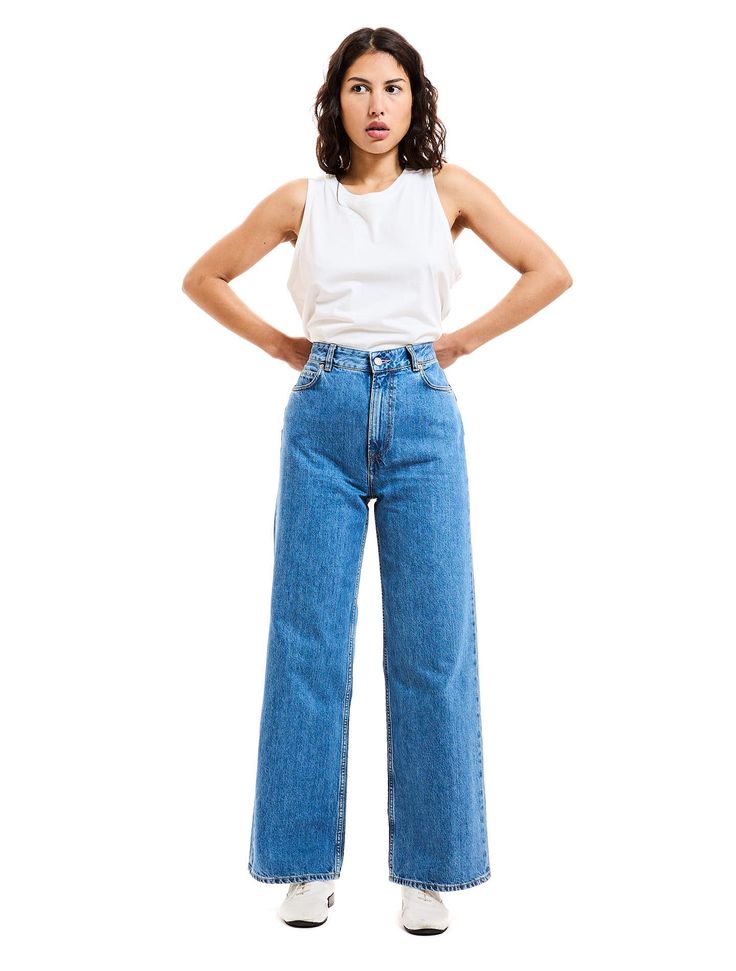 Femme en jeans et débardeur blanc.