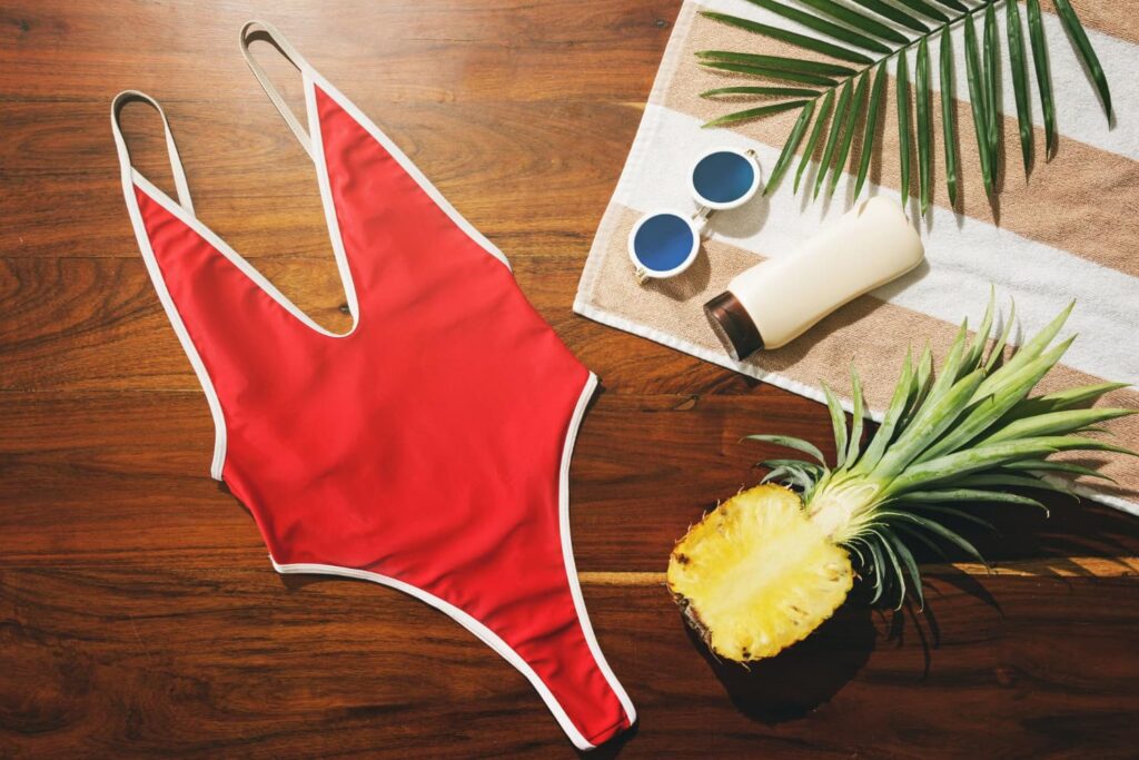 Maillot rouge, lunettes, crème solaire, ananas sur serviette
