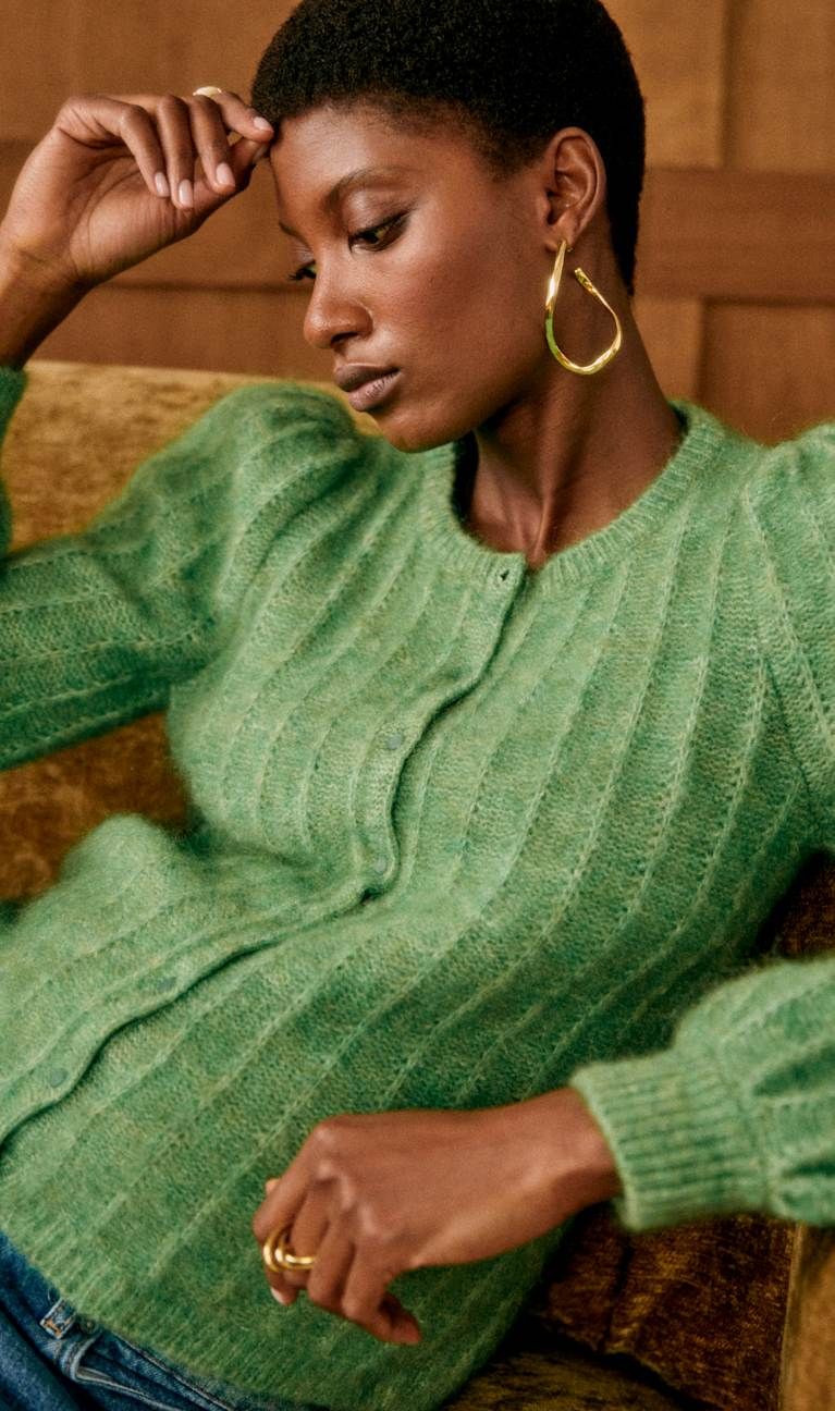 Personne portant un pull vert et boucles dorées.