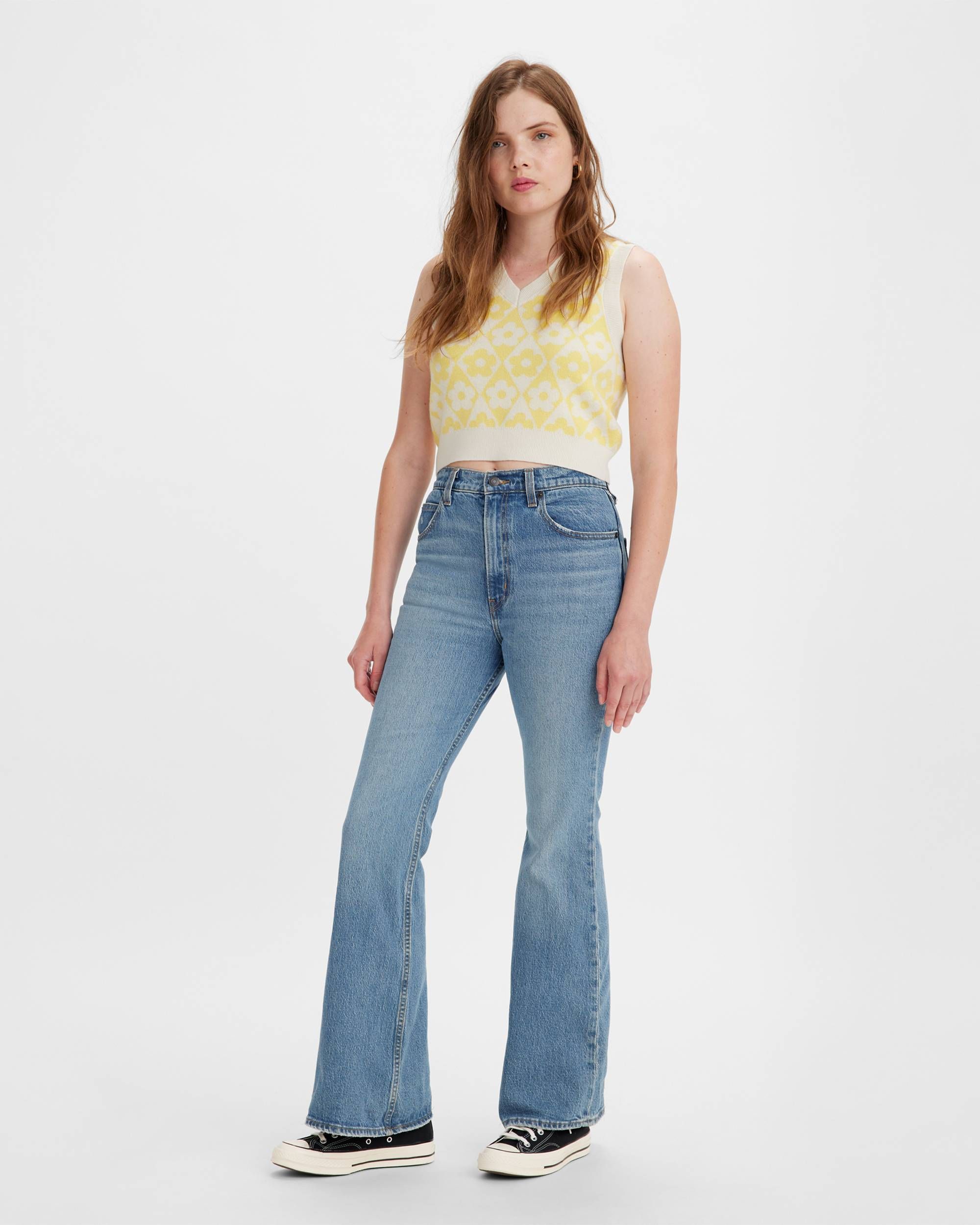 Personne en jeans et débardeur jaune à motifs.