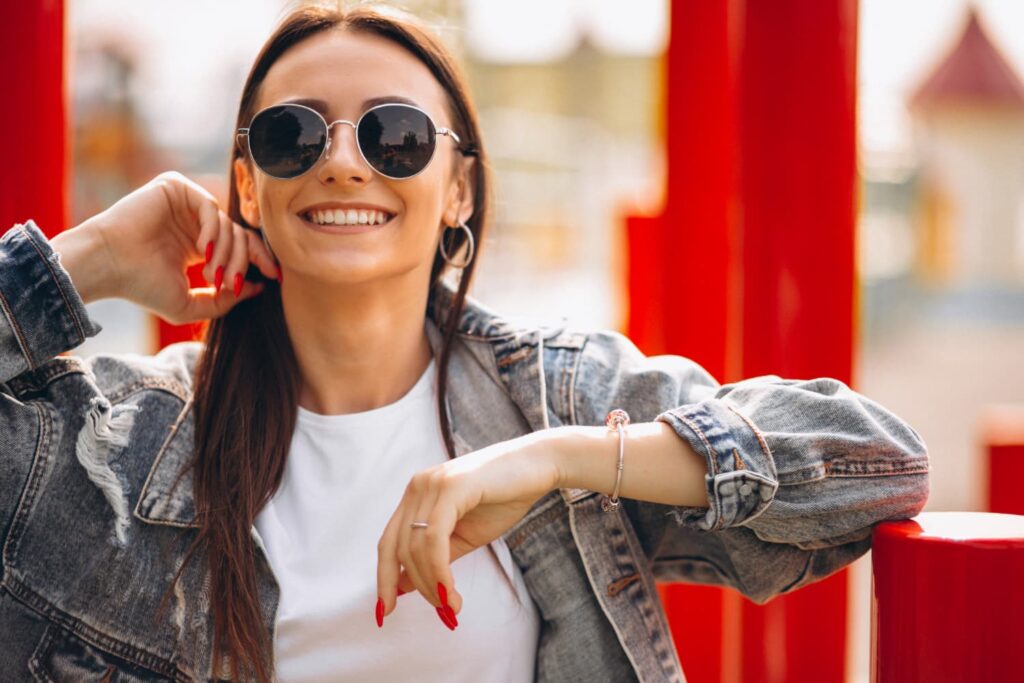 Femme souriante en lunettes de soleil, veste en jean.