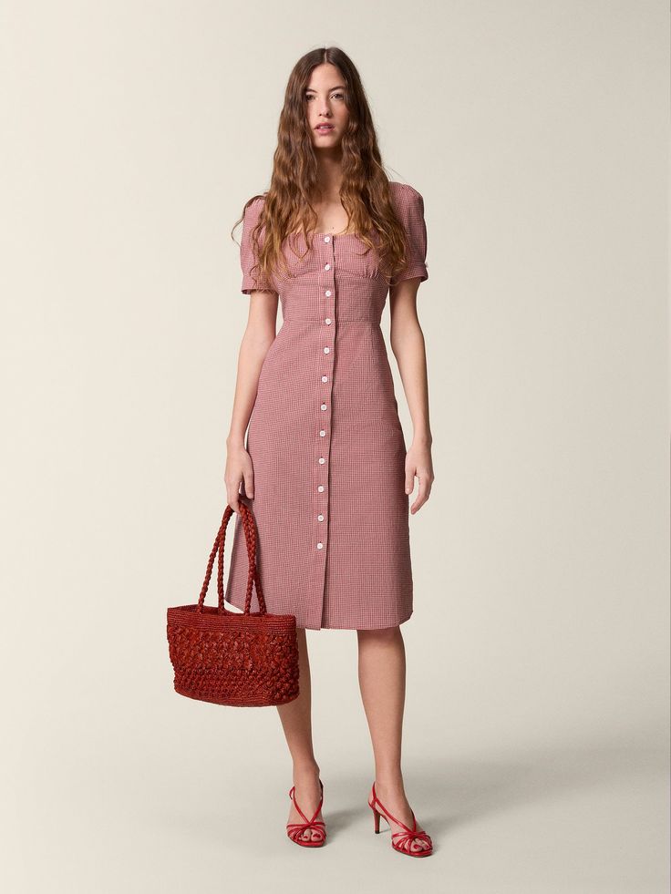 Woman in pink dress, red bag, matching heels.