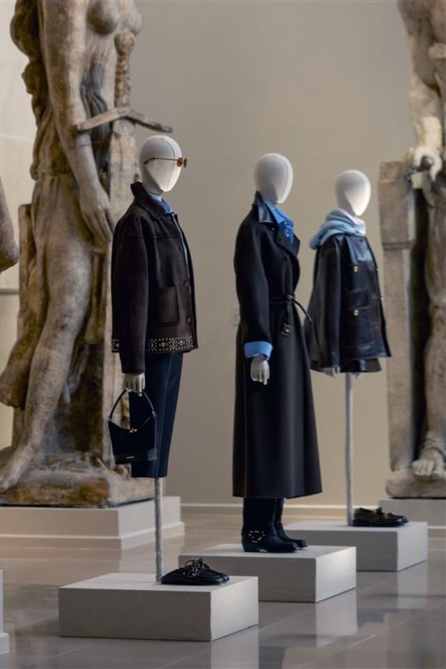 Mannequins displaying stylish clothing in front of classical sculptures.