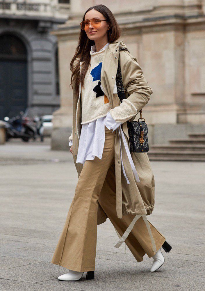 Femme en tenue beige et pull coloré, mode urbaine.