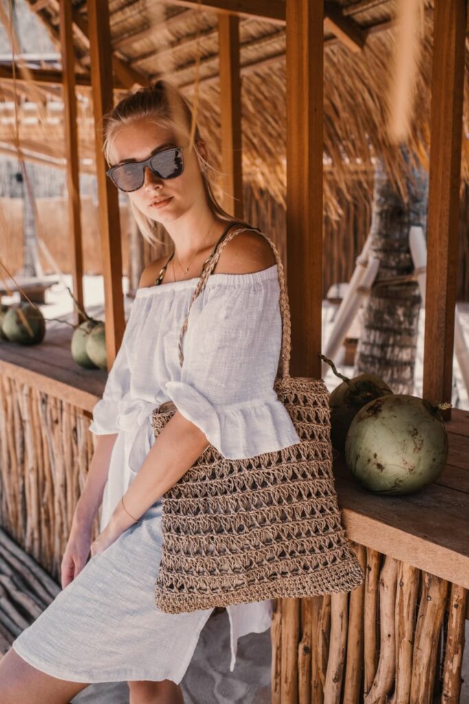 Femme portant robe blanche et sac en paille.