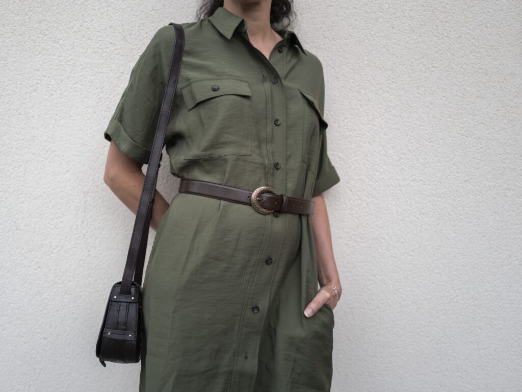 Personne en robe verte avec sac et ceinture.
