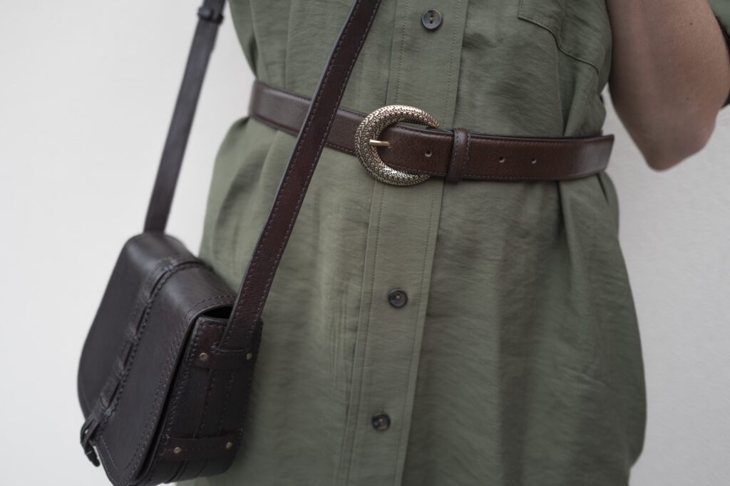 Robe verte, ceinture marron, sac en cuir.