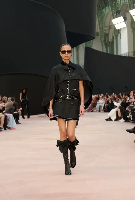 Défilé de mode avec mannequin en tenue noire élégante.